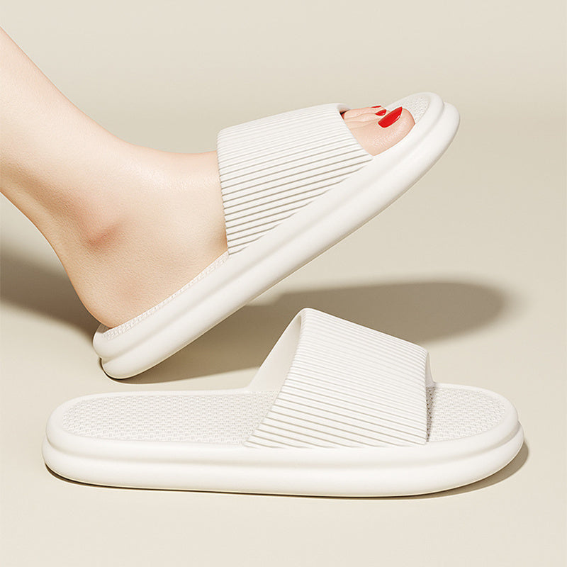 White slide sandals worn by a person on a beige background