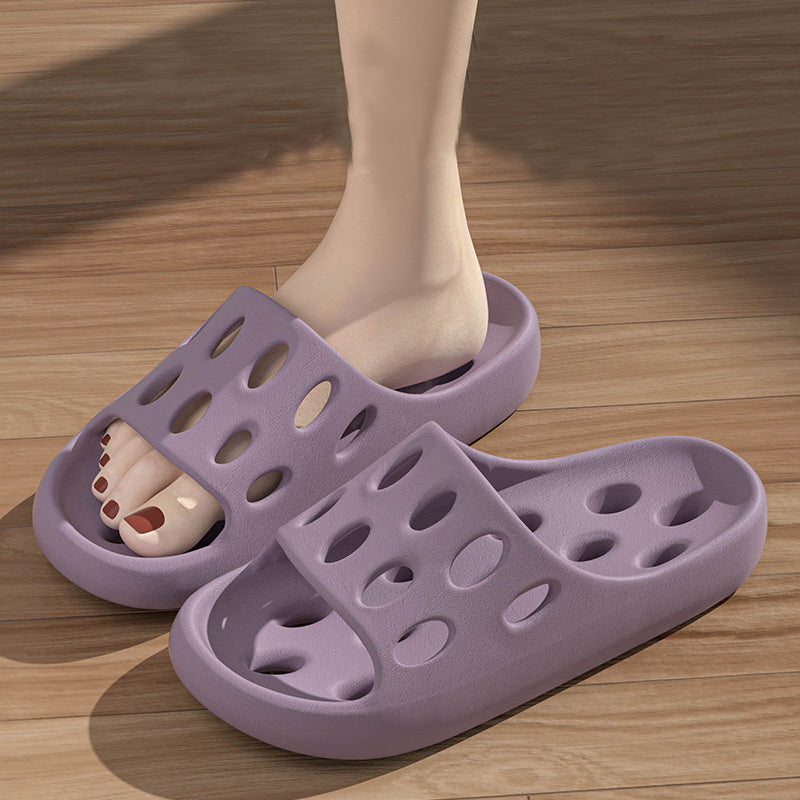 Purple slippers worn by a person on a wooden floor