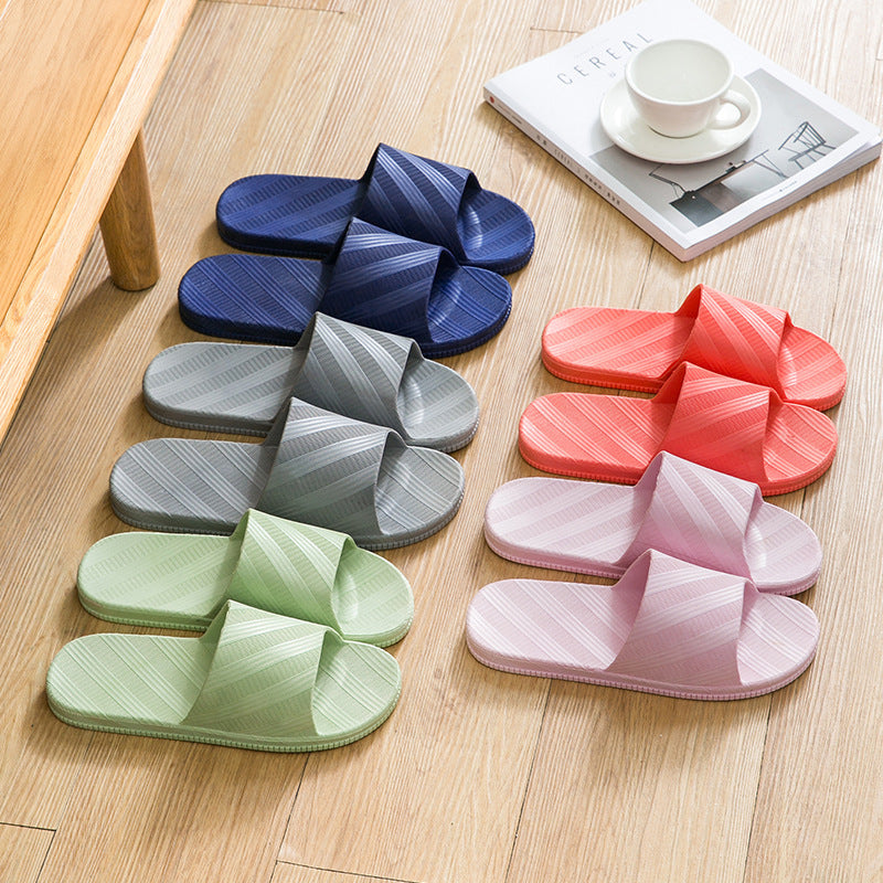 Set of colorful slippers on a wooden floor with a magazine and cup in the background.