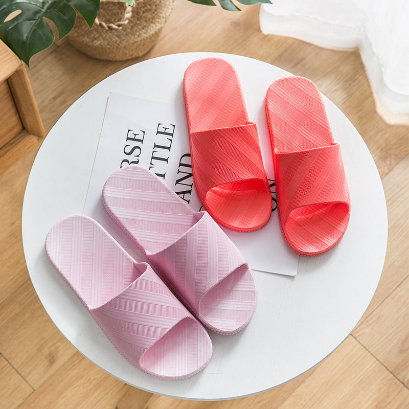 Pink and red slippers on a white plate with a magazine underneath on a wooden surface.