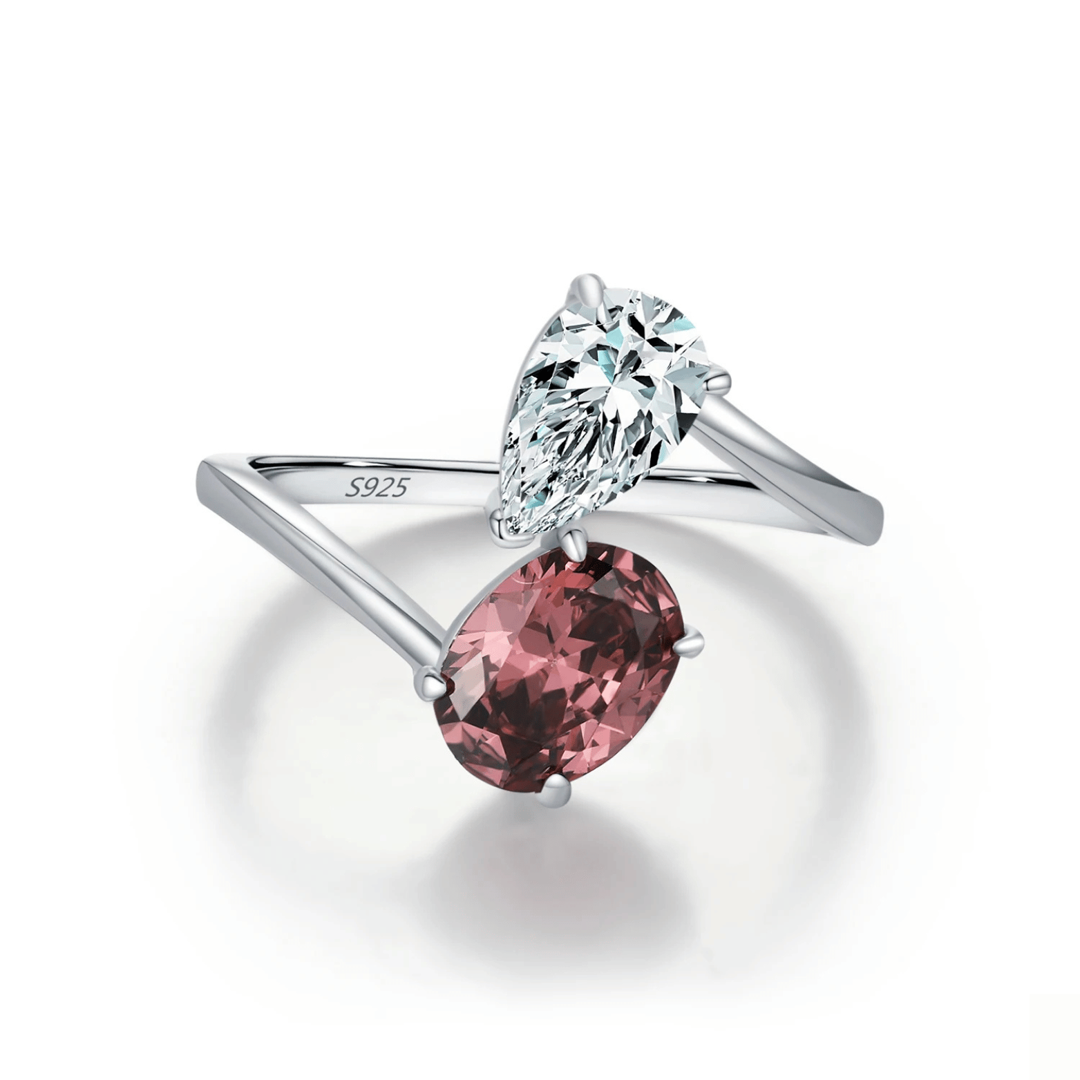 Silver ring with a pink gemstone and clear teardrop gemstone on a white background