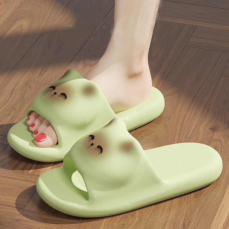 Green cartoon-style slippers worn on a wooden floor